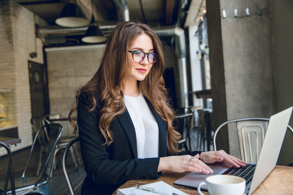 smiling businesswoman typing laptop sitting cafe